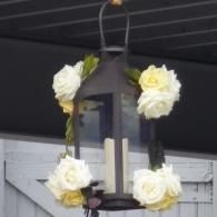 Black lantern decorated with white flowers hanging outdoors