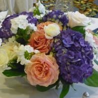 Assorted roses and hydrangeas in peach, purple, and white on a table