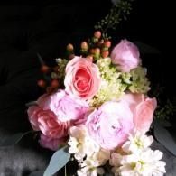Pink and white flower bouquet with roses and white blossoms on a dark background