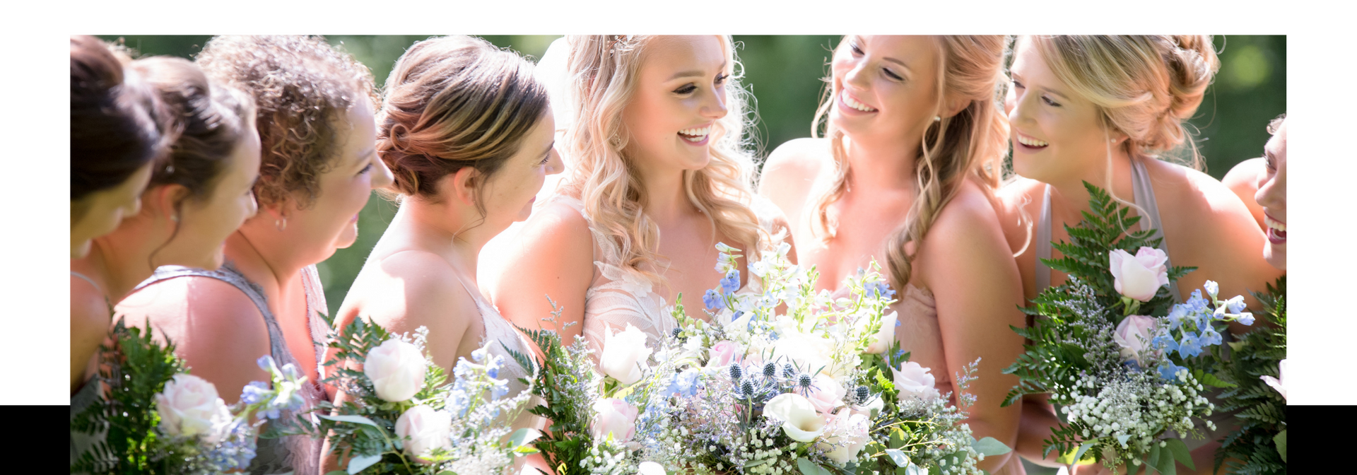 Five women in pink dresses holding white flower bouquets in a sunny outdoor garden ceremony