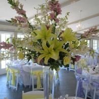 Floral centerpiece with yellow lilies and pink flowers in a decorated banquet room