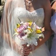 Bride holding a white, pink, and yellow bouquet in a white wedding dress and veil