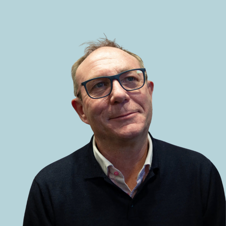 A man wearing glasses and a black sweater is smiling and looking up.