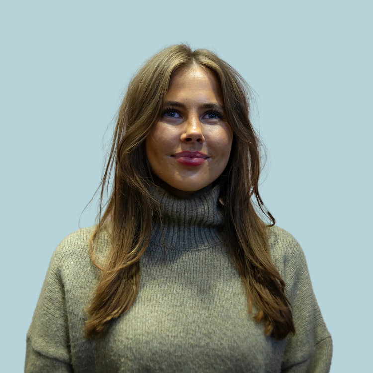 A woman wearing a grey sweater is smiling for the camera