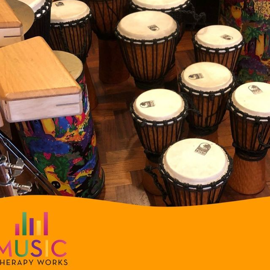 A bunch of djembe drums are sitting on a wooden floor