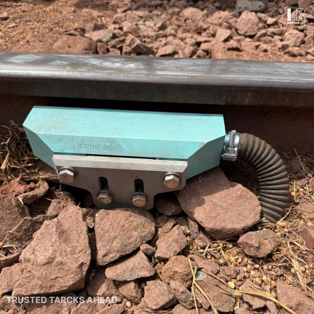 Intertechrail's wheel sensor is on a railroad track on rocky ground, with a black corrugated conduit.