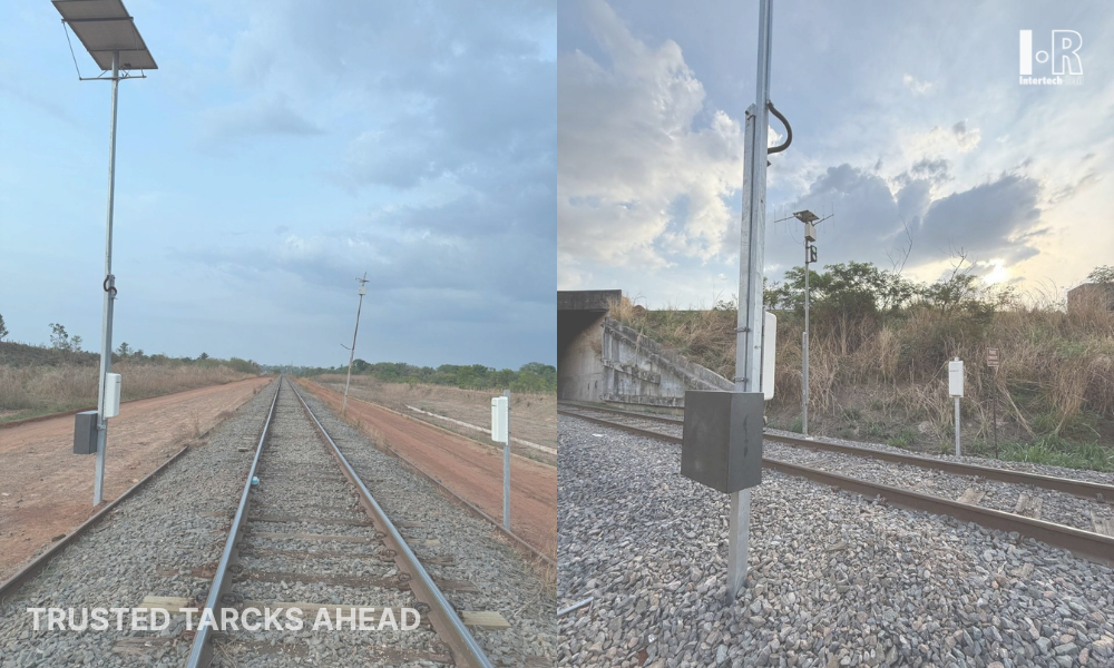 Railway tracks stretching into the distance beside gravel, signal posts, and a cloudy sky at dusk.