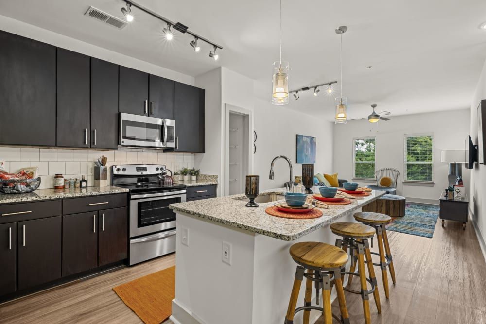 Apartment kitchen with black cabinets, stainless steel appliances, granite countertops, and a large island at Skyline West in Atlanta, GA.