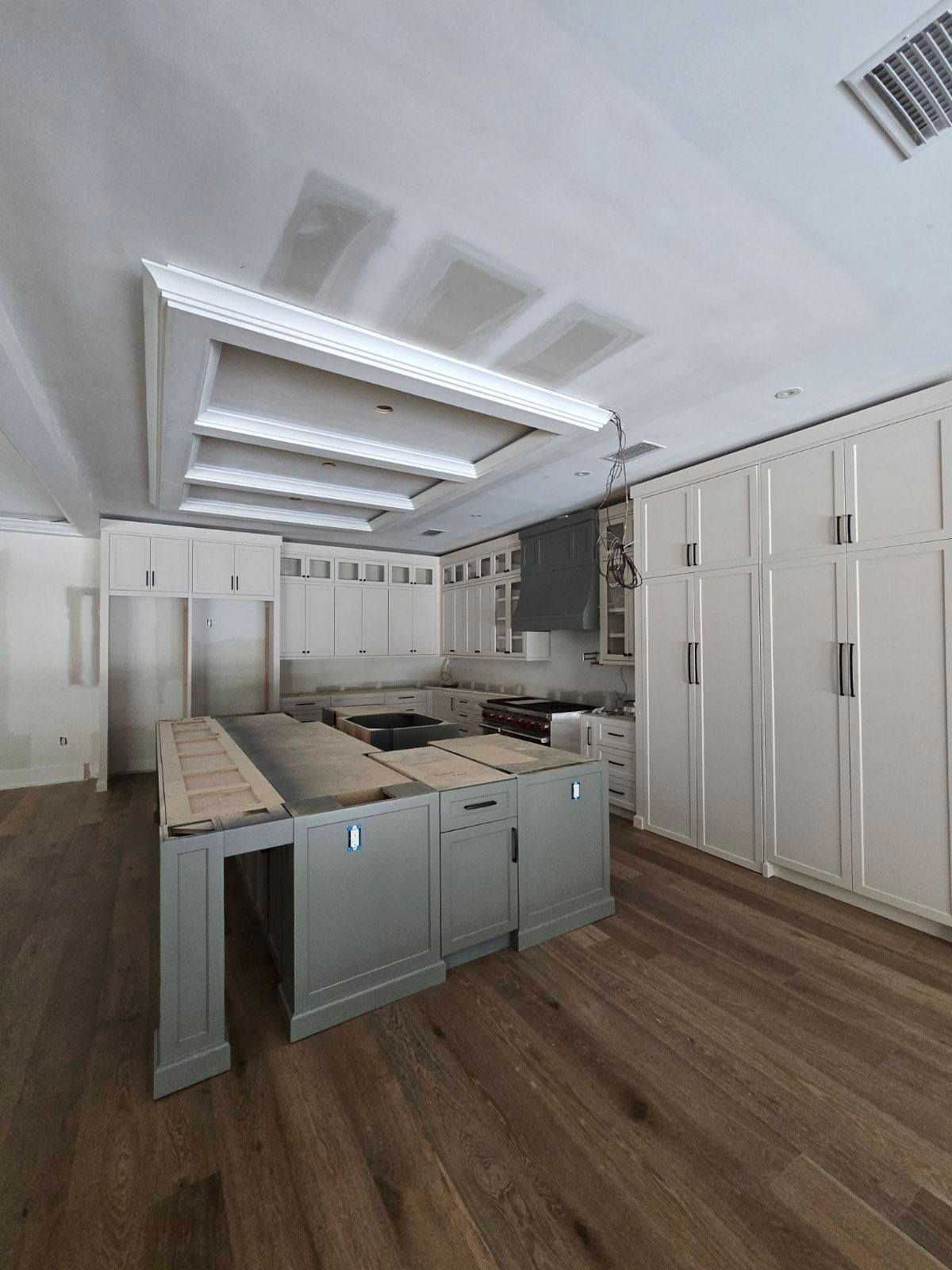 A kitchen is being built with a large island in the middle of the room.