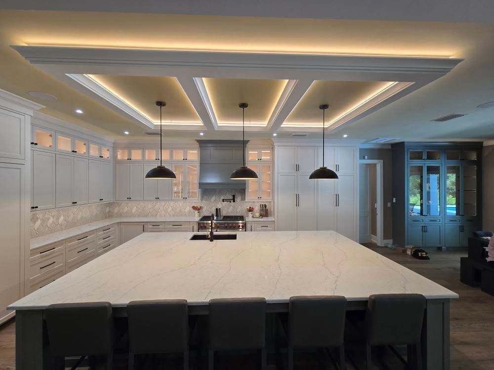 A kitchen with white cabinets and a large island in the middle.