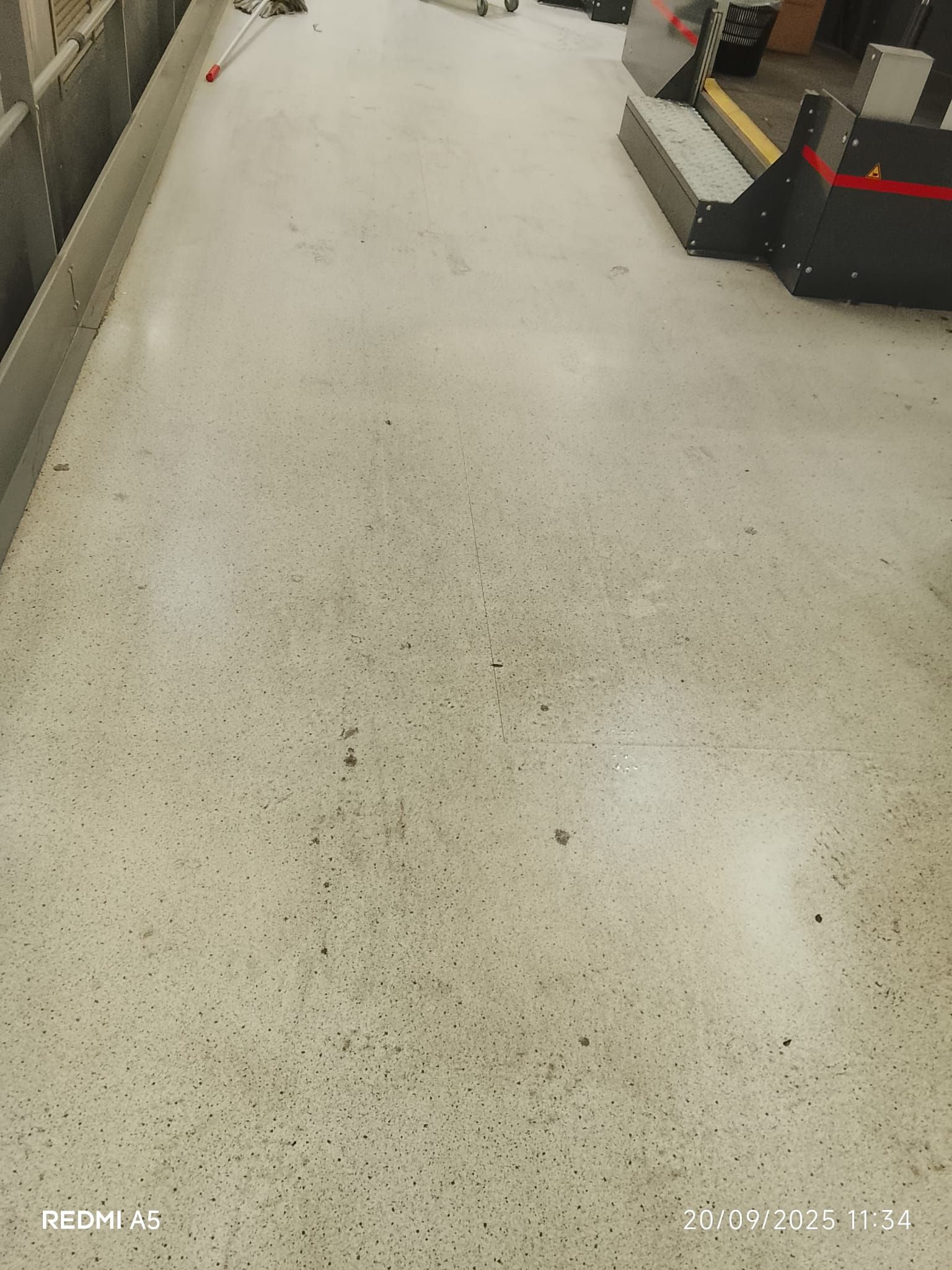 Corridoio di un negozio con pavimento chiaro e casse sul lato destro.