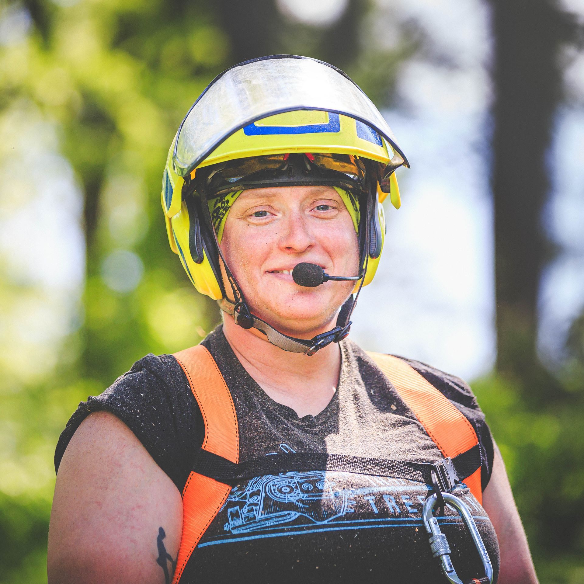 A woman wearing a helmet and a microphone smiles for the camera