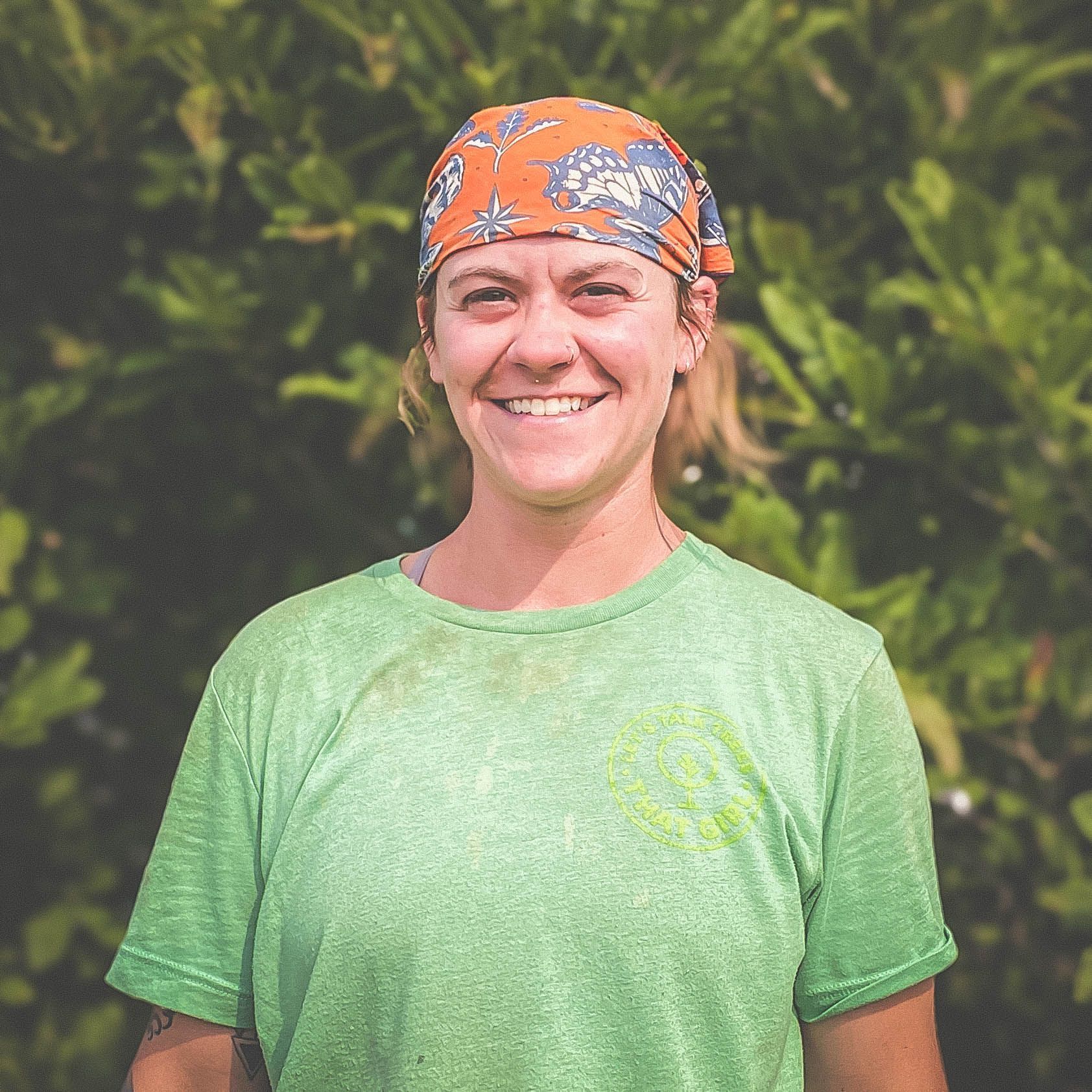 A woman wearing a green shirt and an orange headband is smiling.