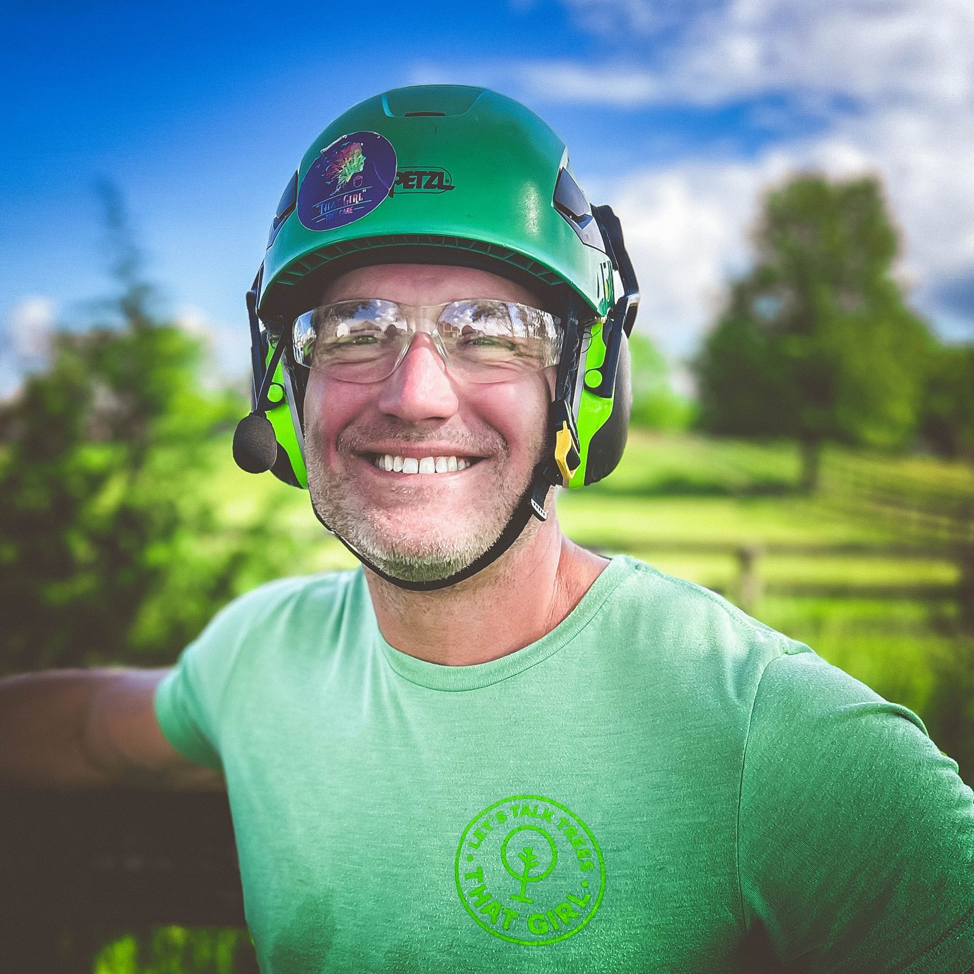 A man wearing a green helmet and glasses is smiling