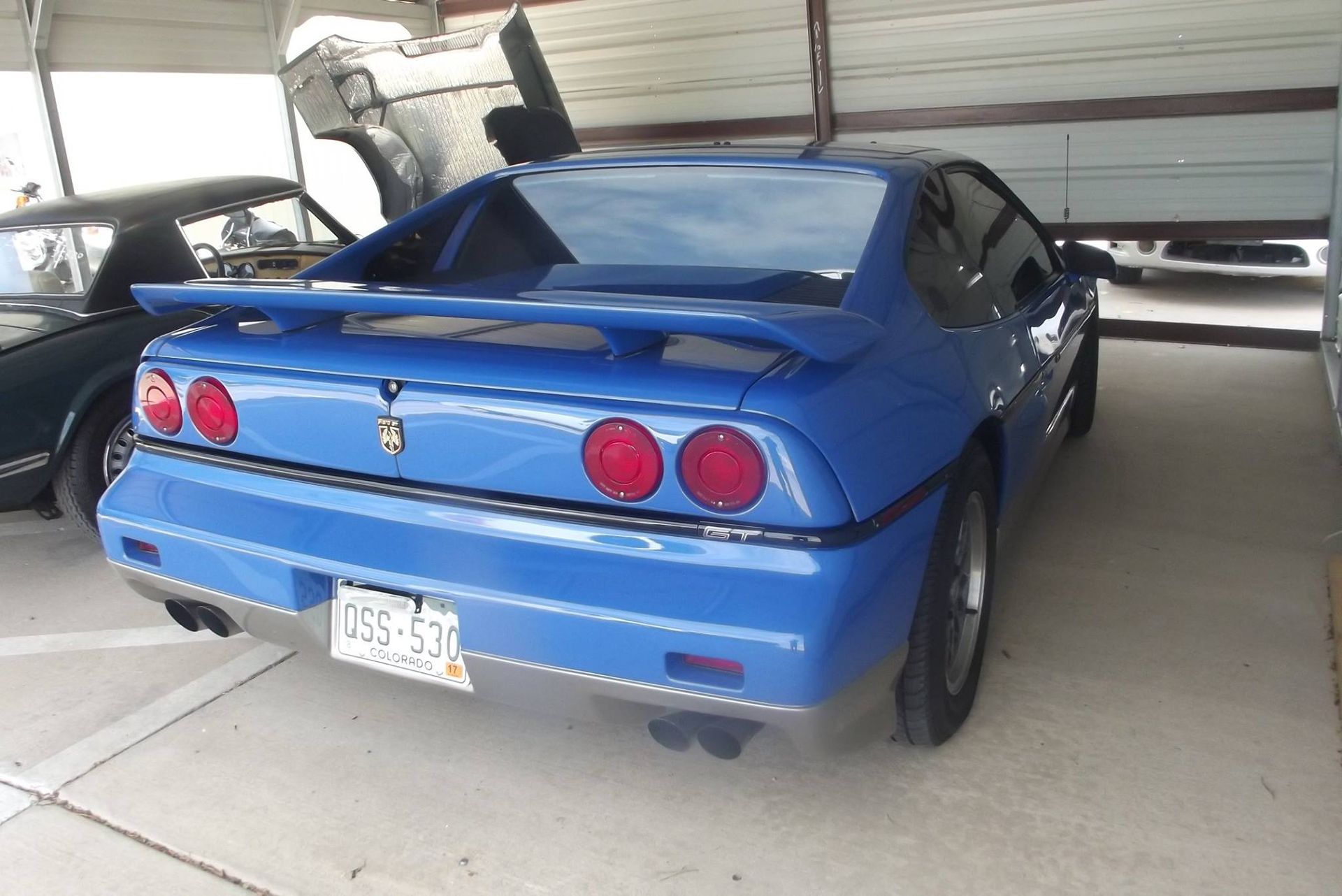A blue sports car is parked in a garage