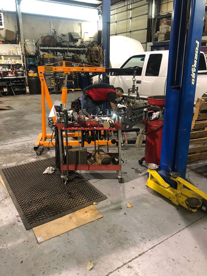 A man is working on a truck engine in a garage.