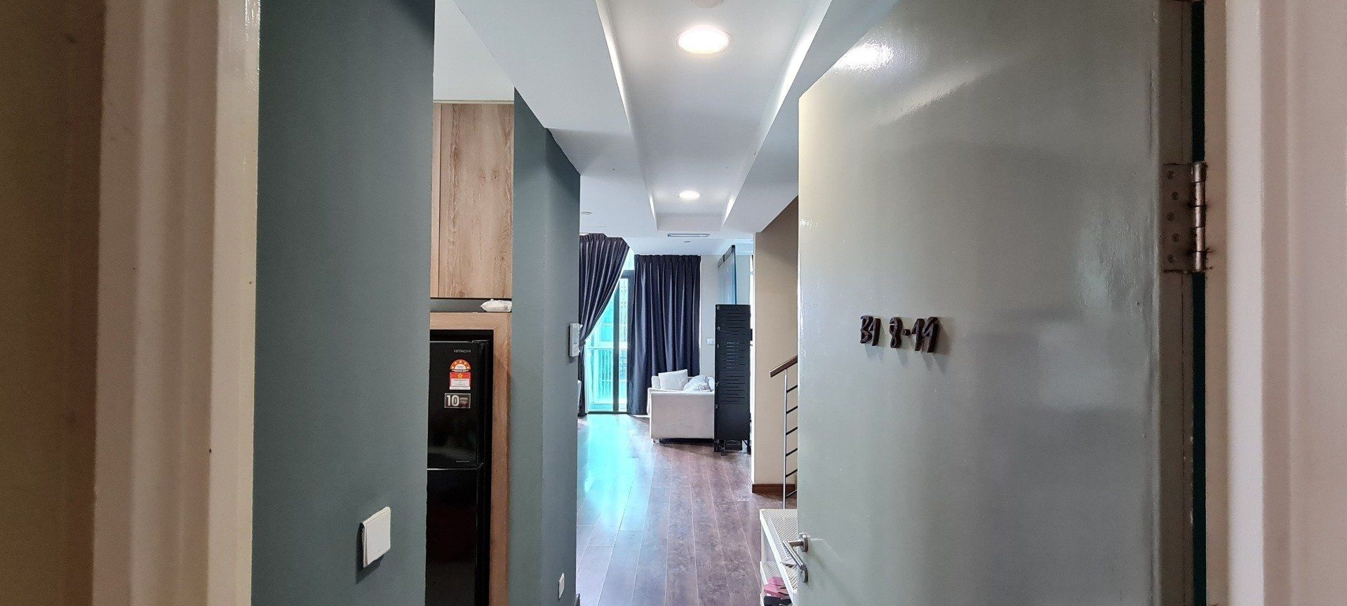 A hallway with a door leading to a living room and a kitchen.