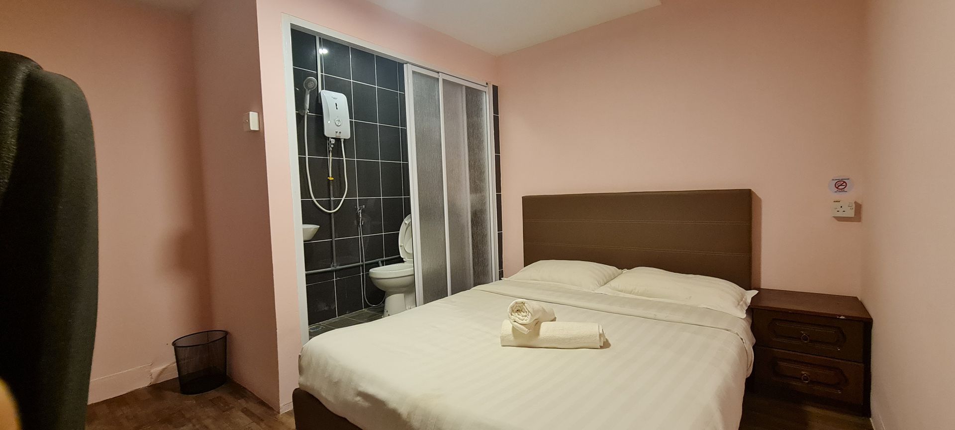 A bedroom with a bed , nightstand , and toilet.