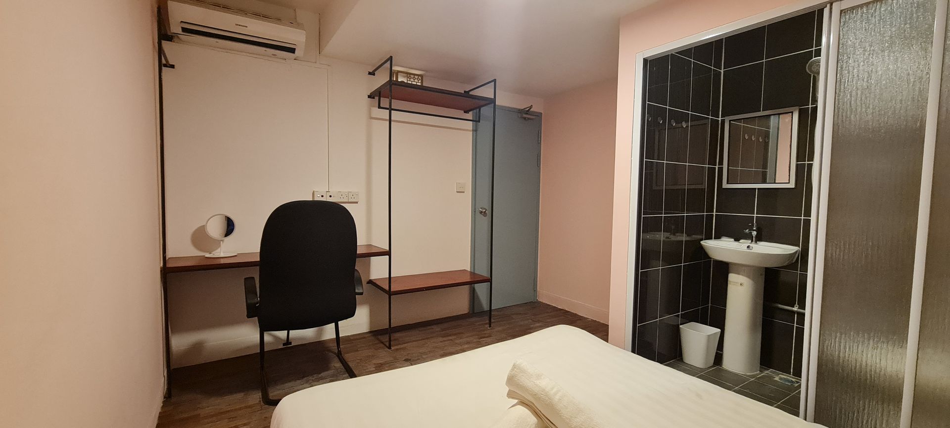 A bedroom with a bed , desk , chair and sink.