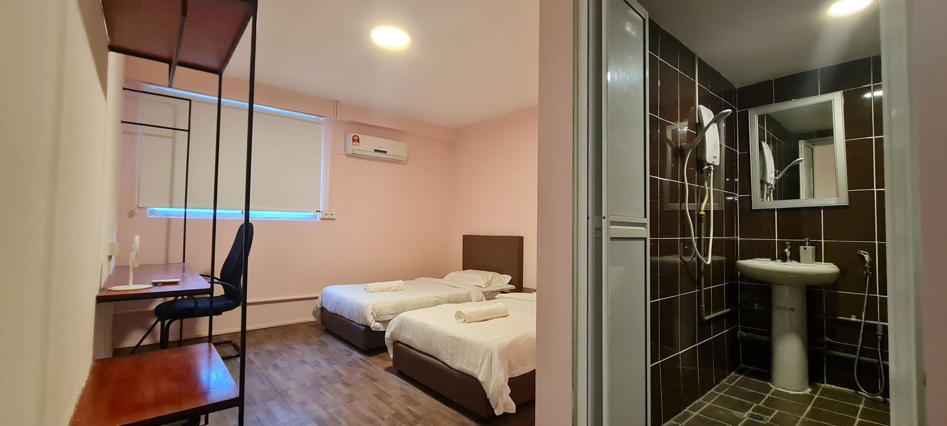 A hotel room with two beds and a bathroom with a sink.