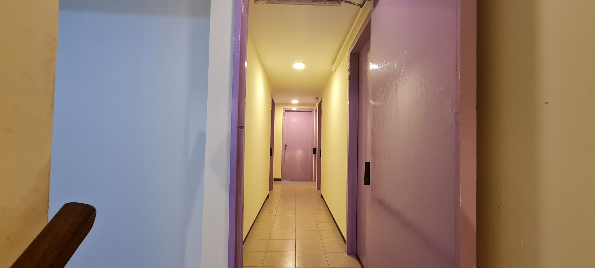 A long hallway with purple doors and a staircase.