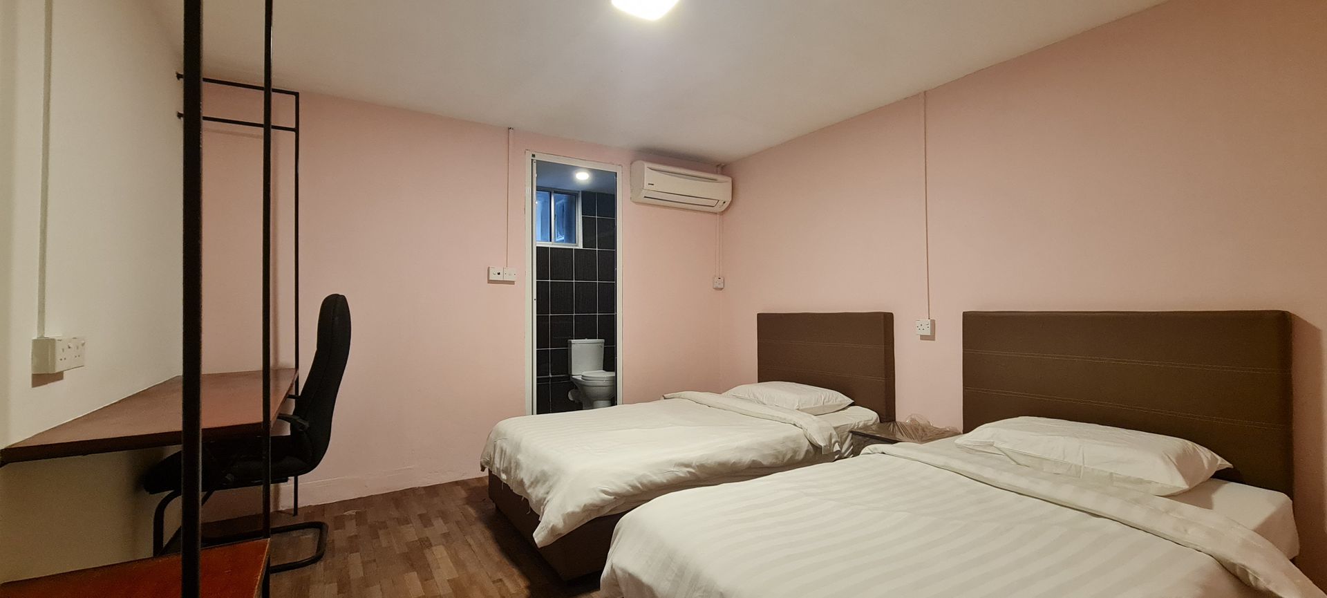 A hotel room with two beds and a desk.