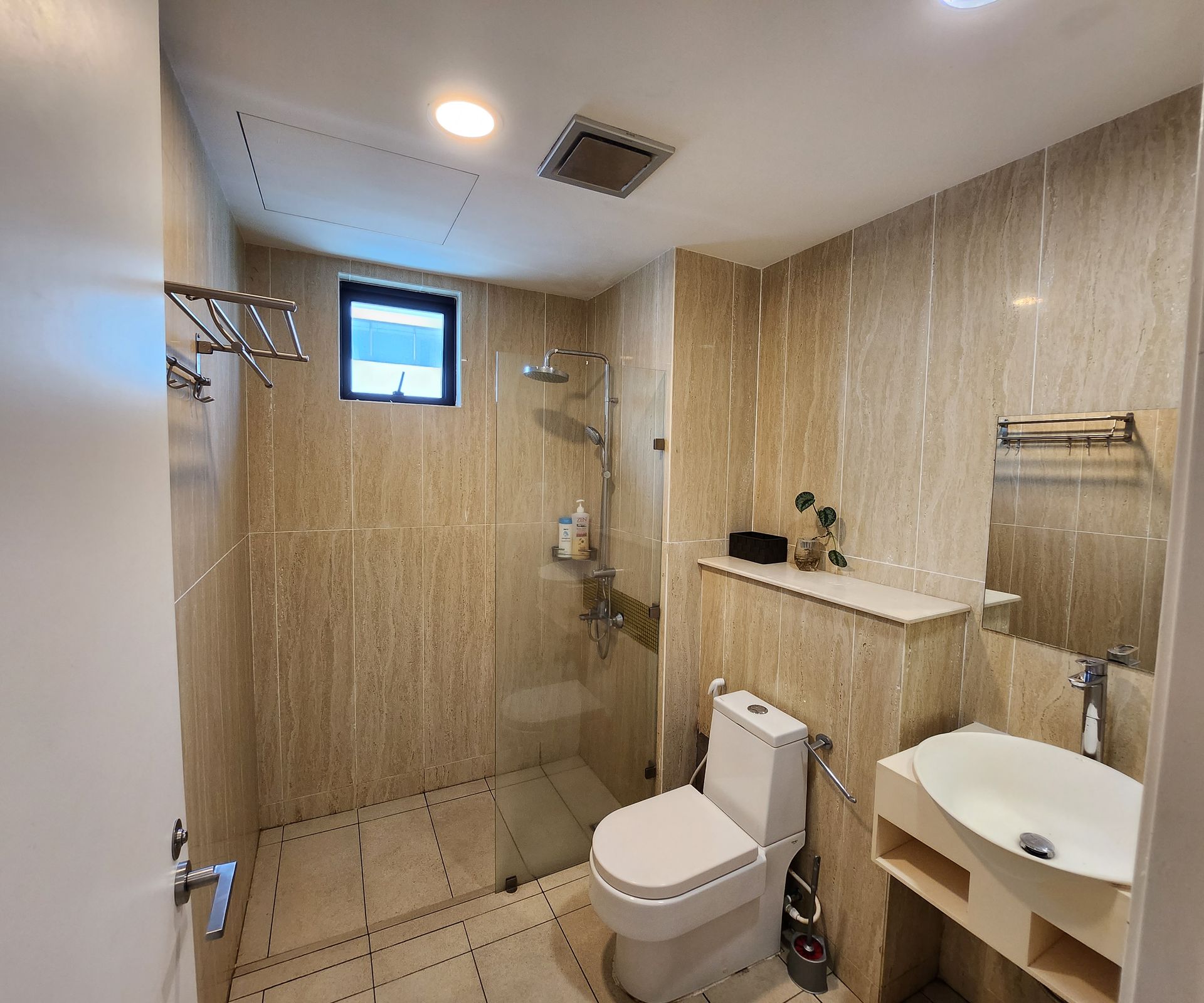 A bathroom with a toilet , sink and shower.