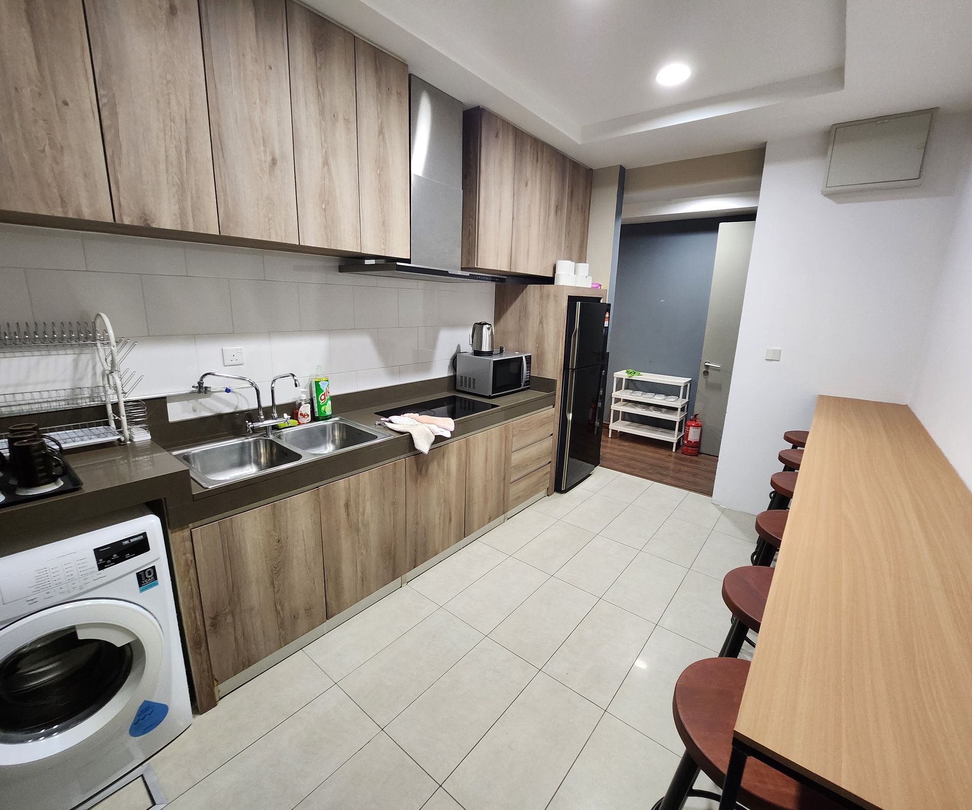 A kitchen with wooden cabinets , a washer and dryer , a sink , and a table.