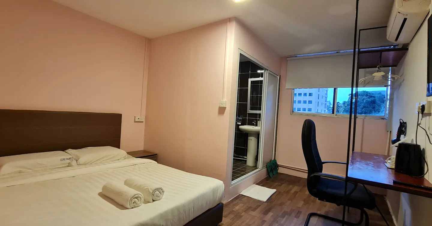 A hotel room with a bed , desk and chair.