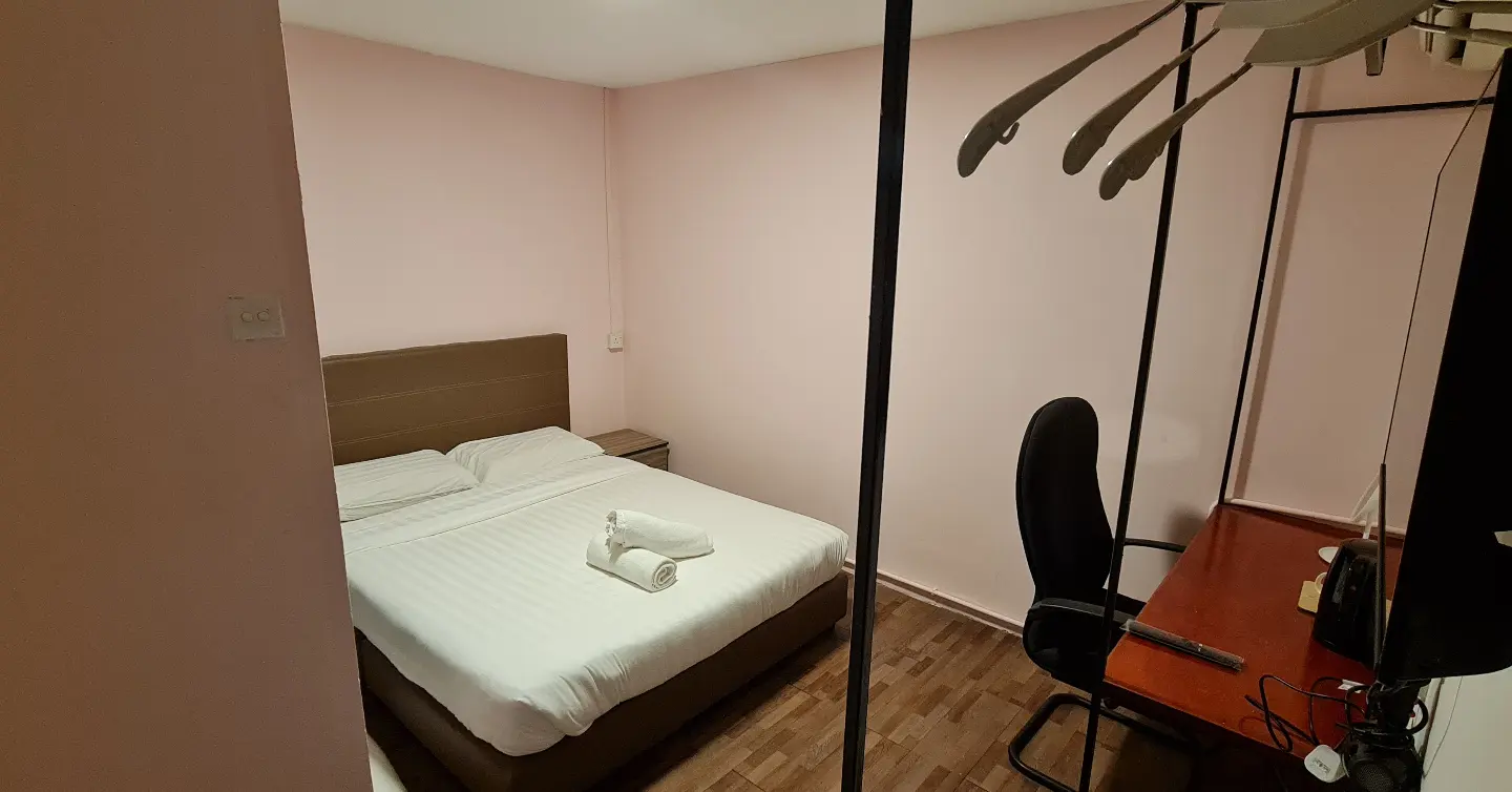 A hotel room with a bed , desk and chair.