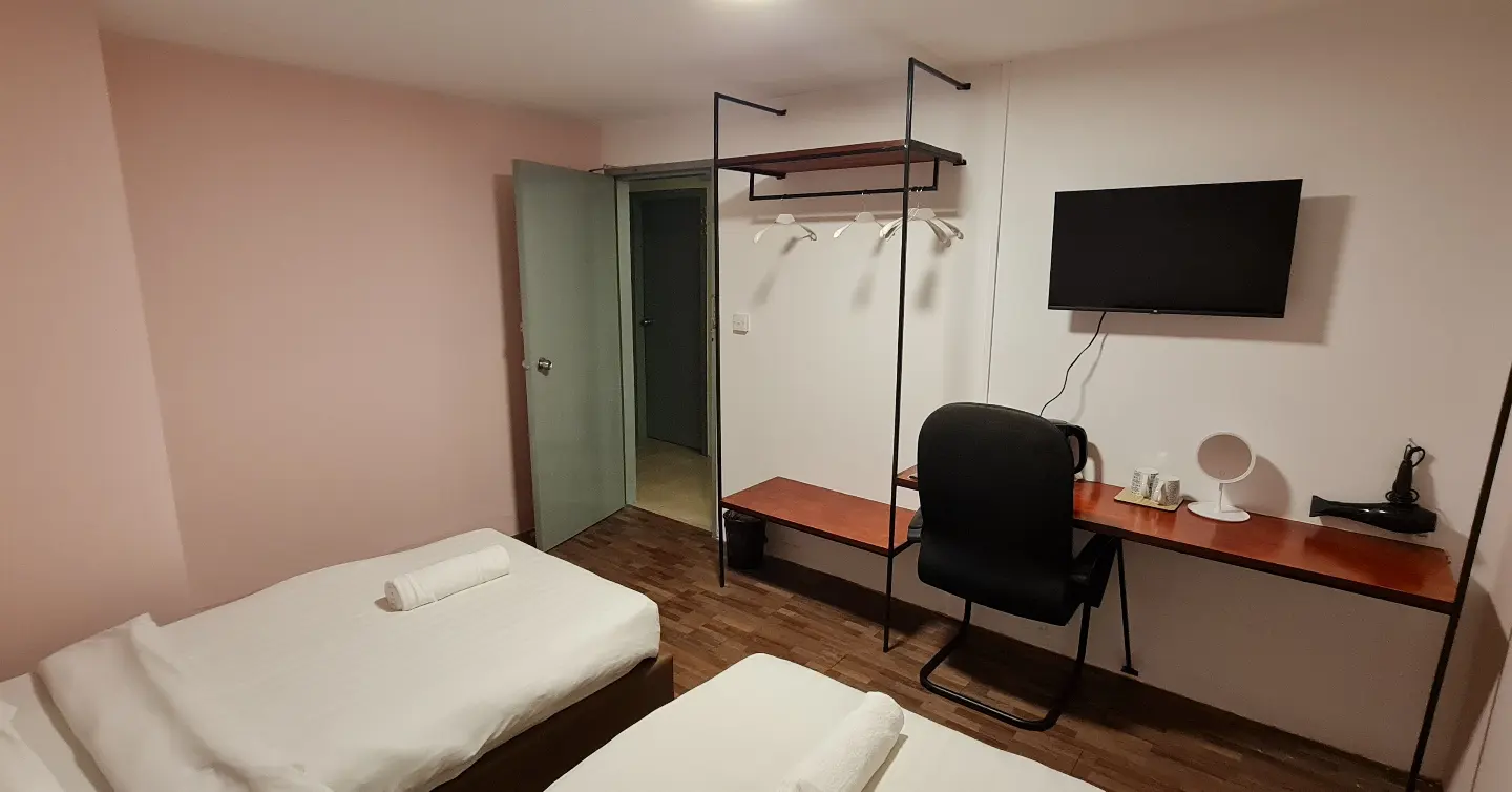 A hotel room with two beds , a desk and a flat screen tv.