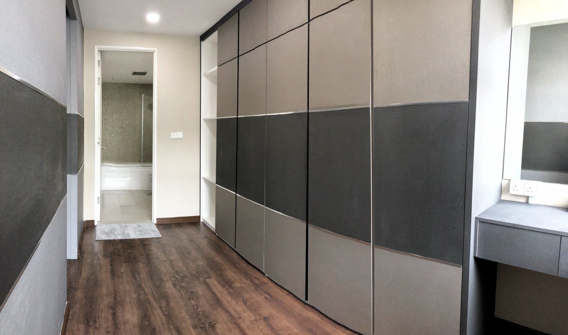 A long hallway with sliding doors leading to a bathroom and a dressing table.