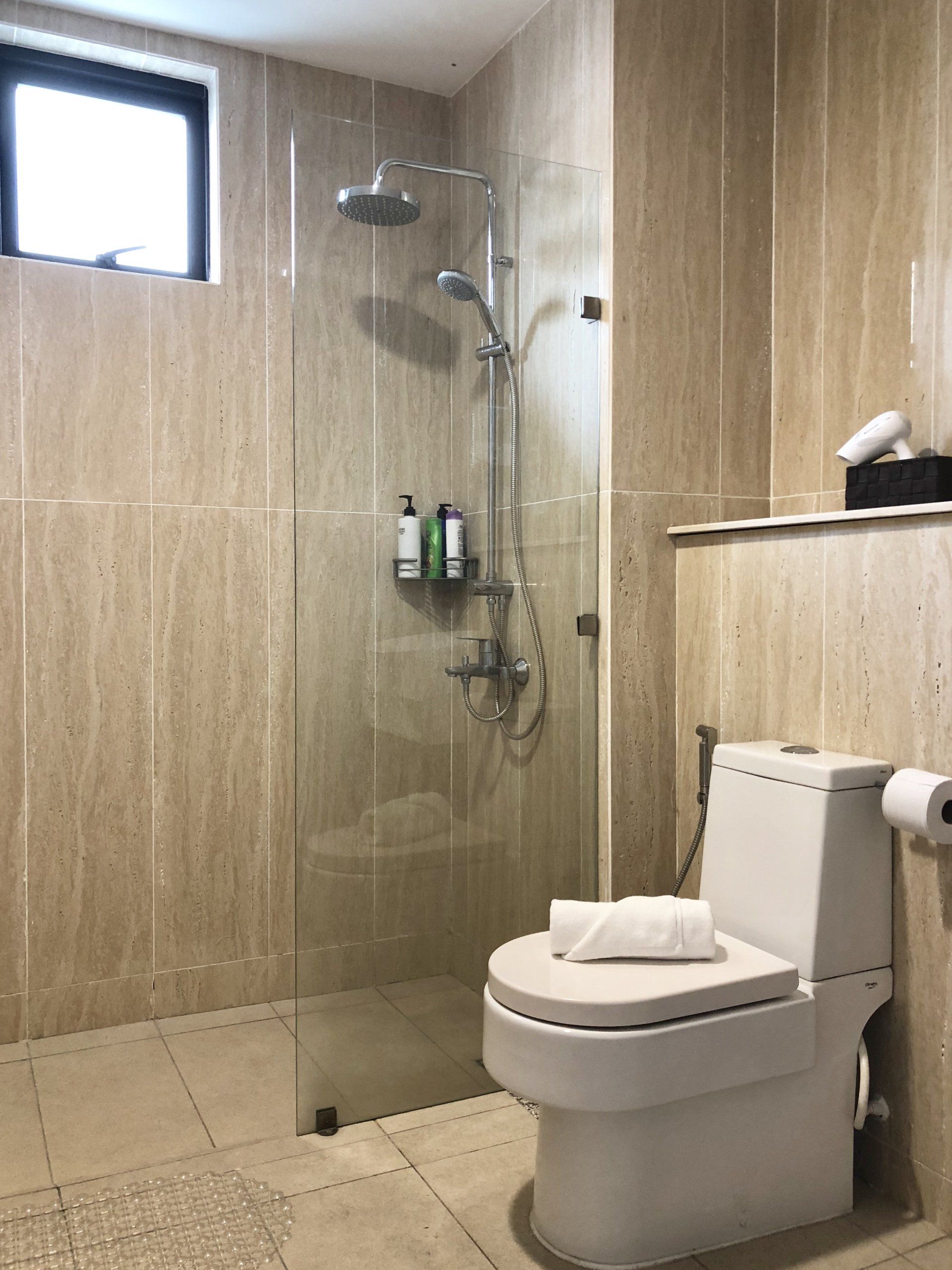A bathroom with a toilet , shower , and window.
