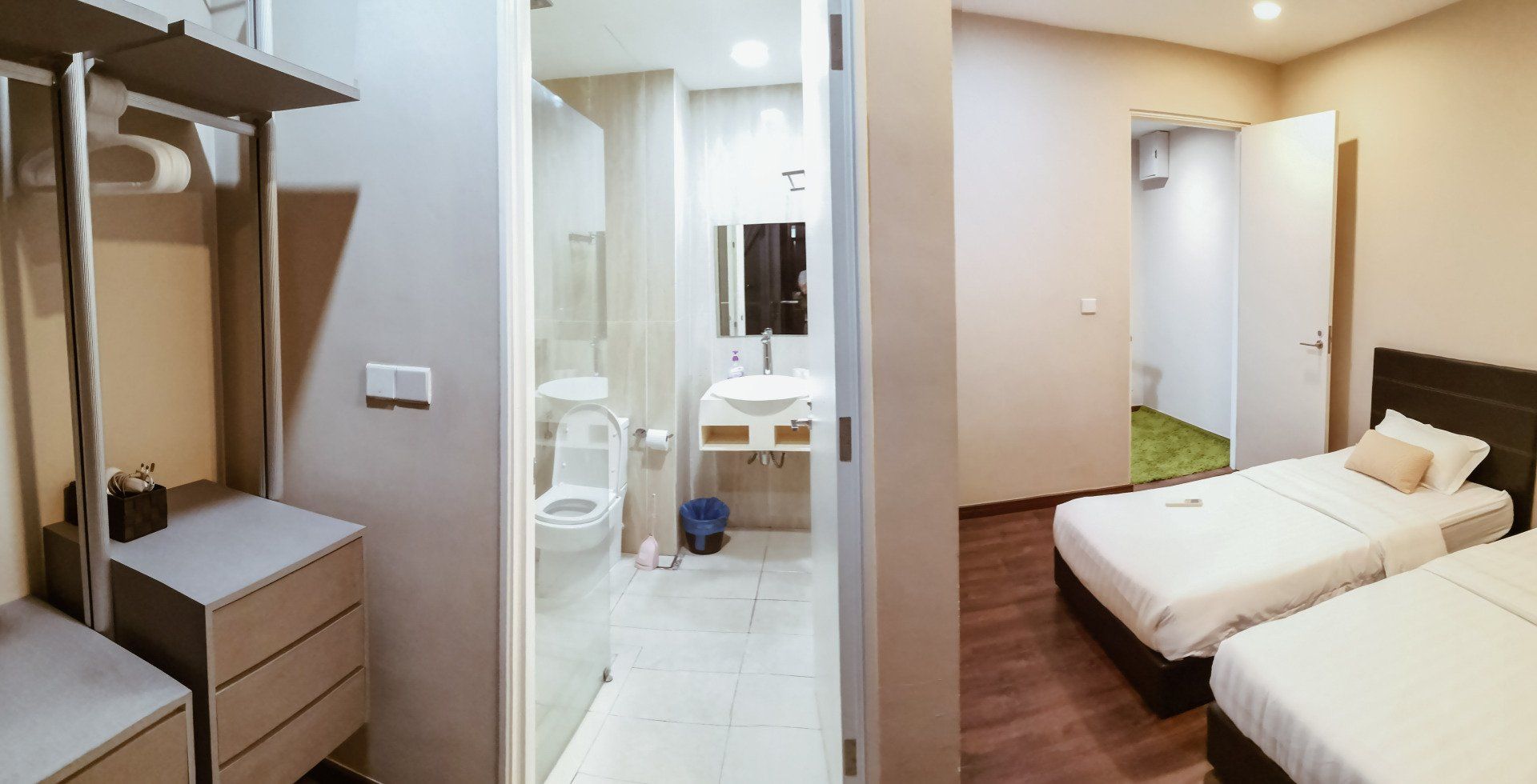 A bedroom with two beds and a bathroom with a toilet.