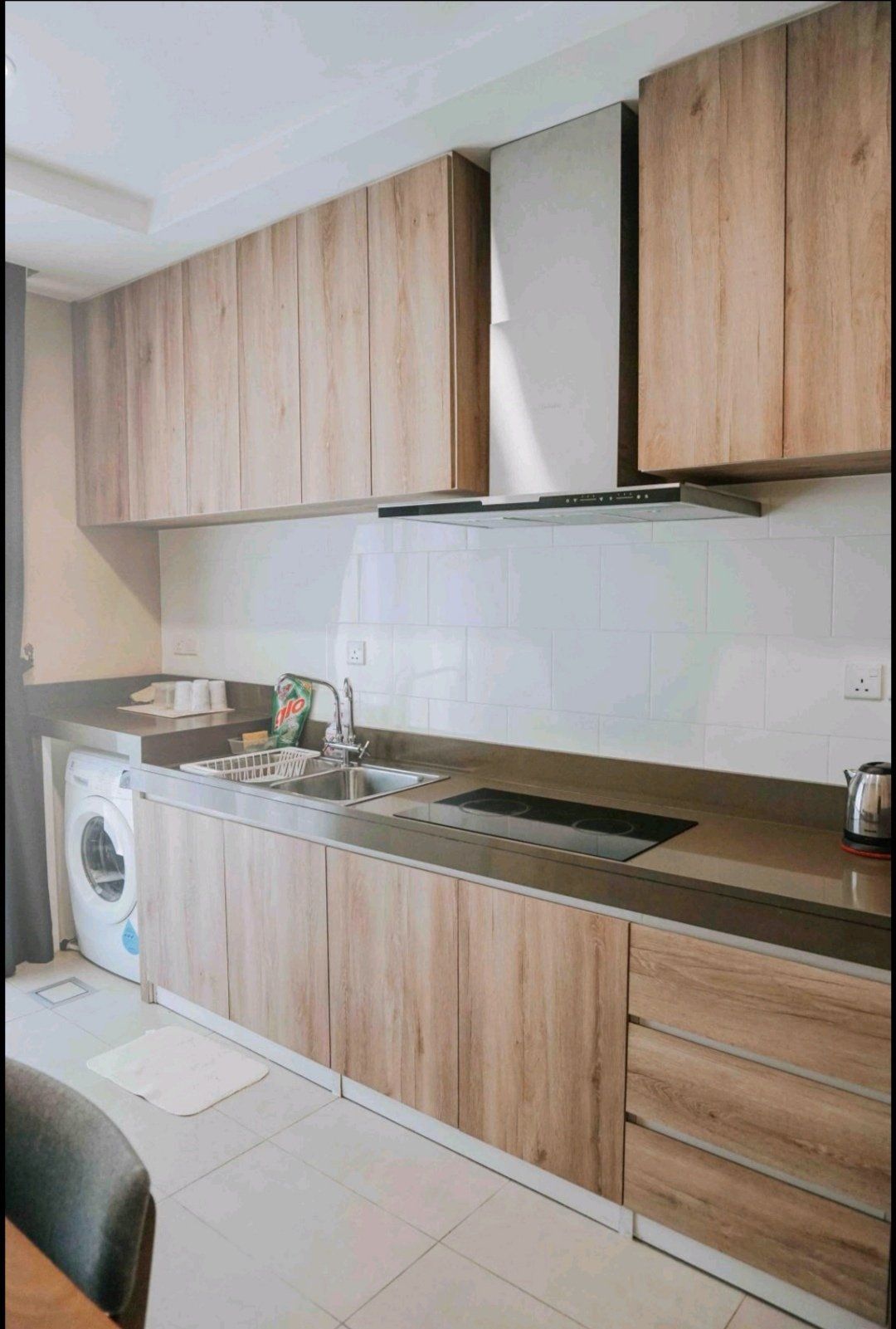 A kitchen with wooden cabinets , a sink , a stove , and a washer and dryer.