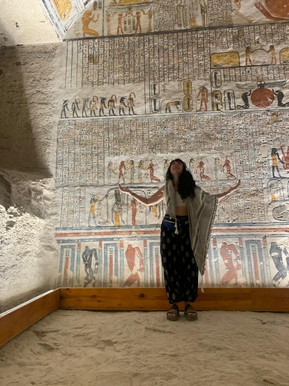 Manos colocando cartas del tarot sobre una superficie negra con cristales, velas y joyas.