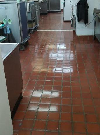 Une cuisine avec carrelage rouge et appareils électroménagers en acier inoxydable.