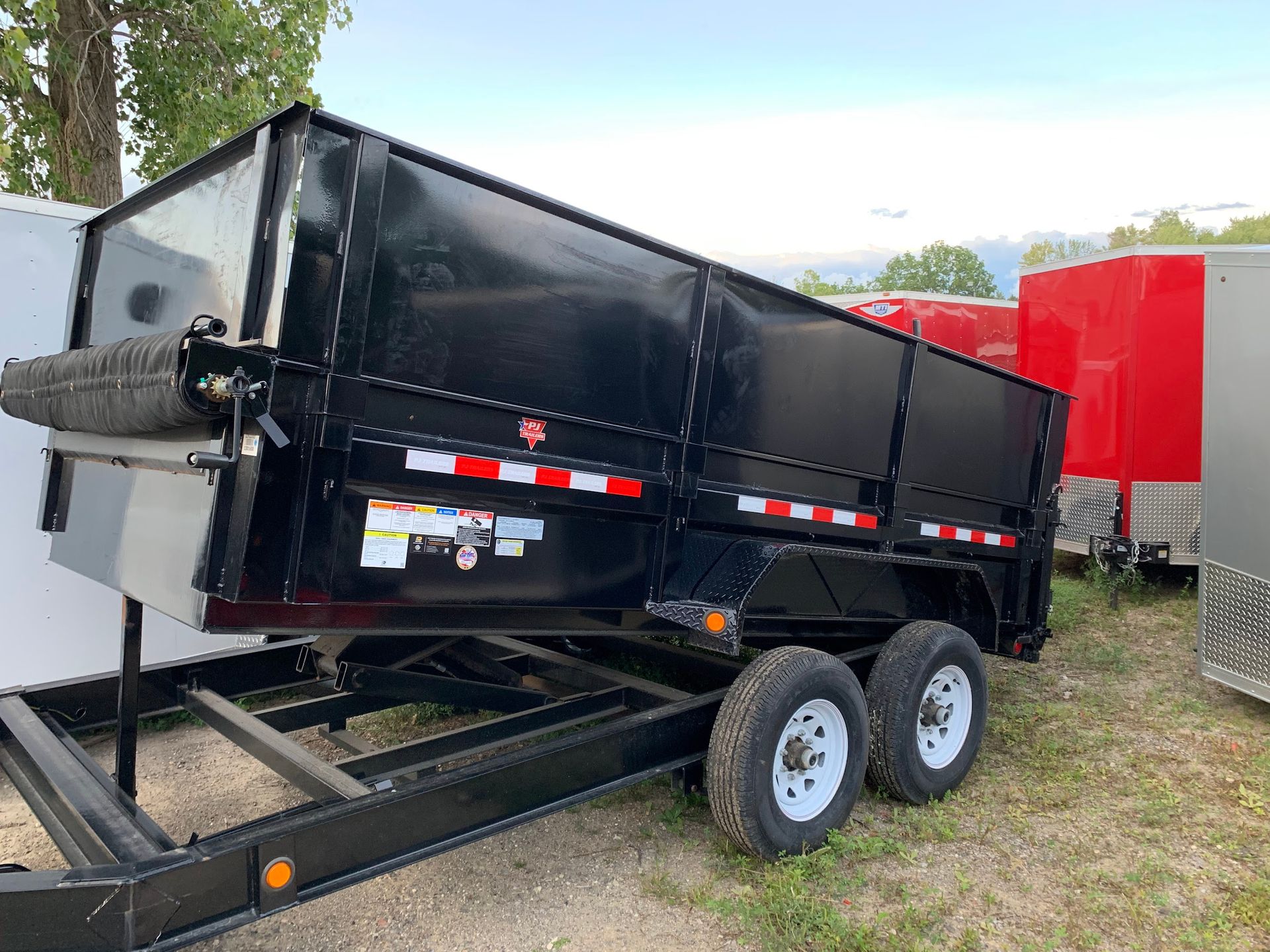 A dump trailer is sitting on top of a trailer in a field.
