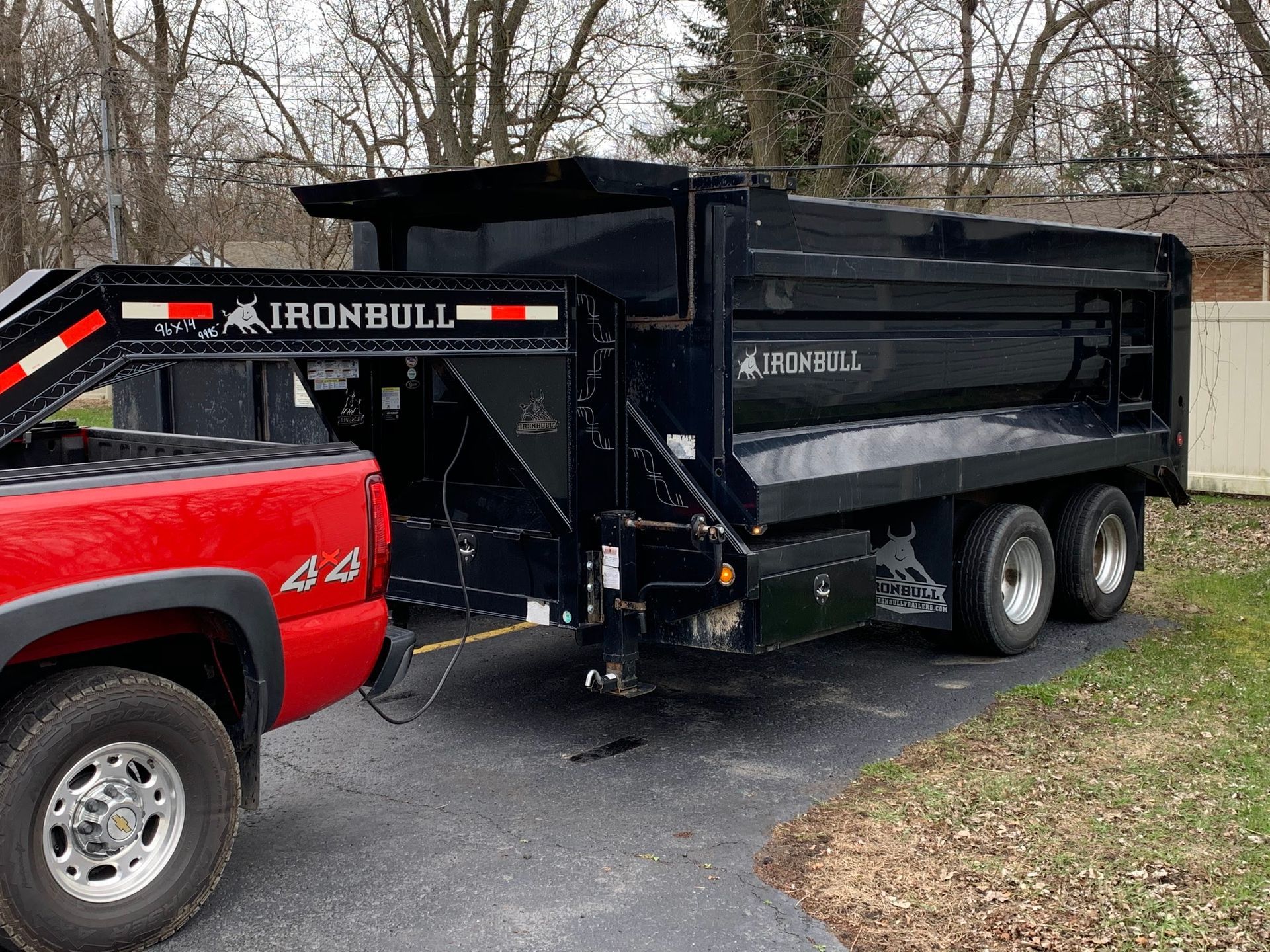 A red truck is towing a dump truck on a trailer.