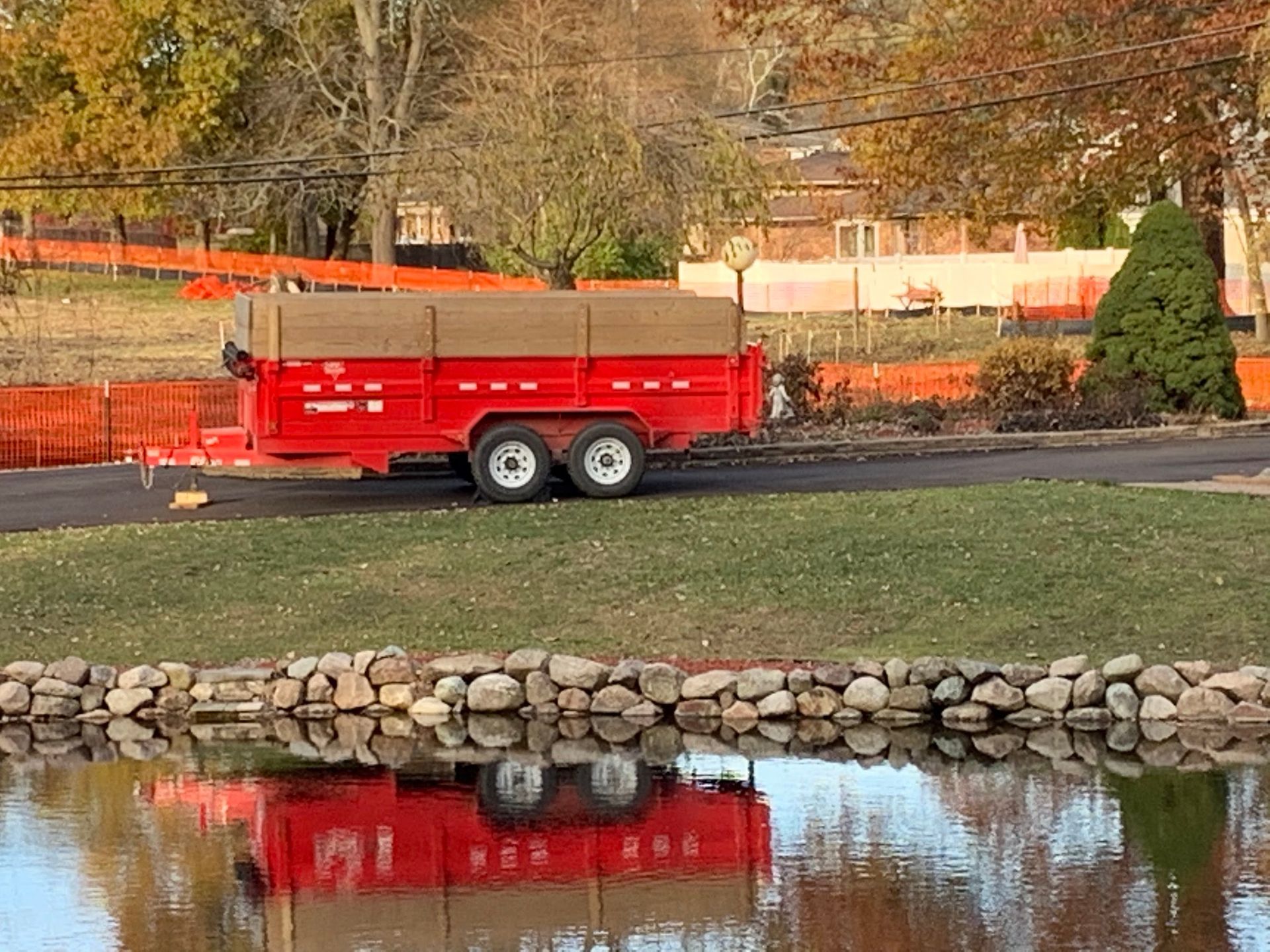 A red trailer is parked next to a body of water