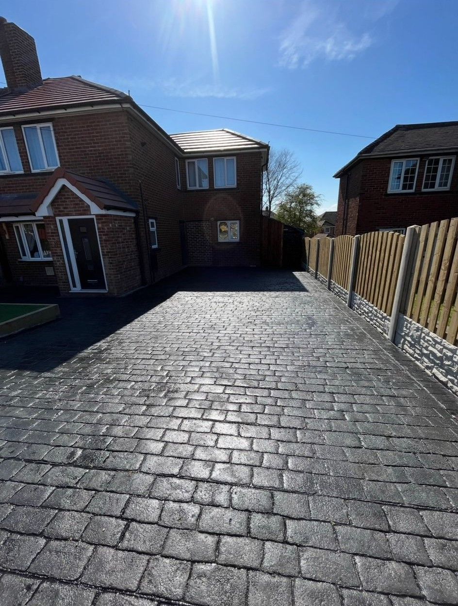 Paved driveway beside red-brick houses under a bright blue sky