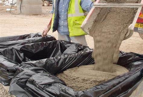 Concrete being poured into a black-lined container at a construction site