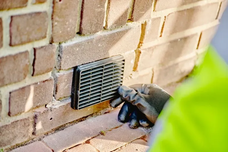 Een vuilgeel plafond met een enkele hangende gloeilamp en donkere houten balken.