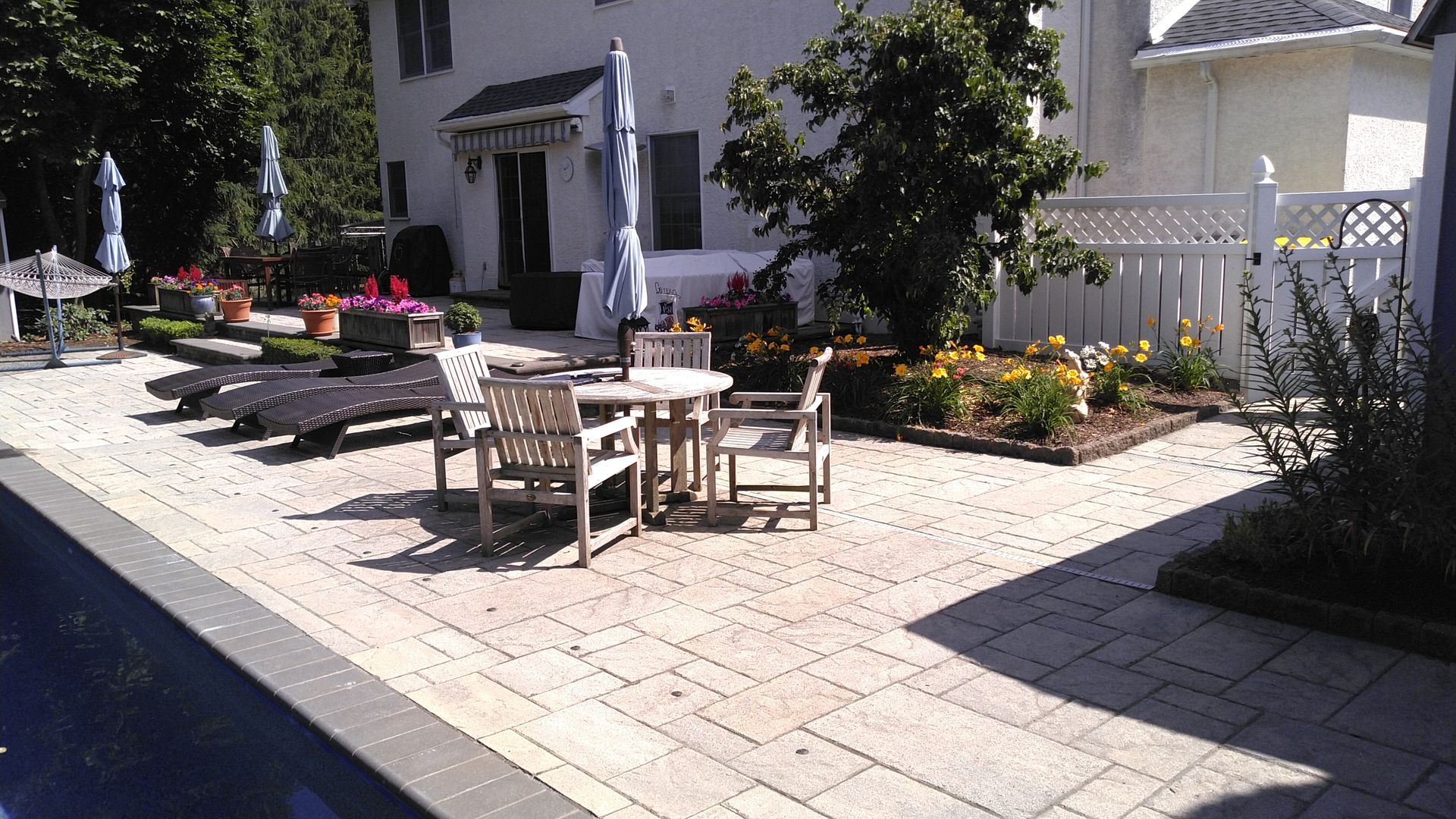 Outdoor patio with tables, chairs, umbrellas, and flower beds beside a building