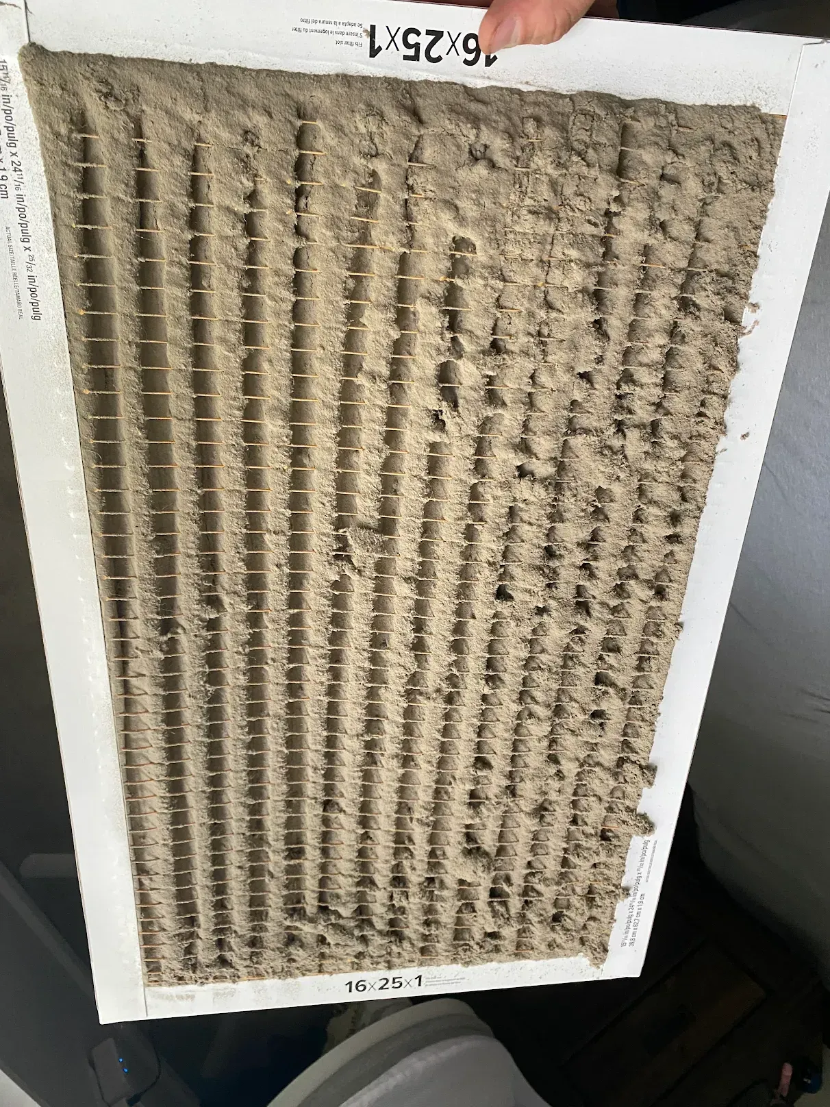 A person is holding a dirty air filter in their hand.