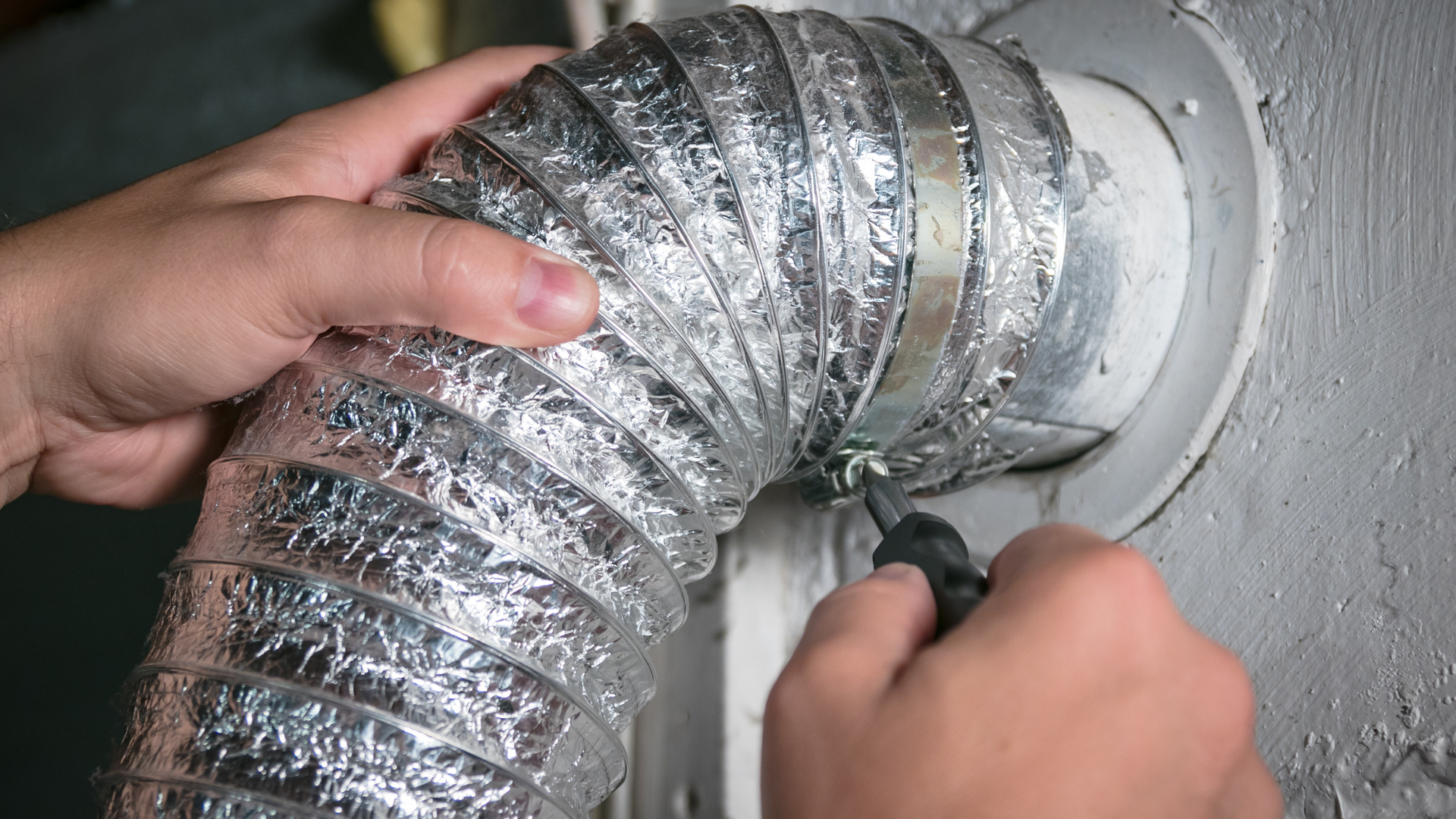 A person is fixing a duct with a screwdriver.