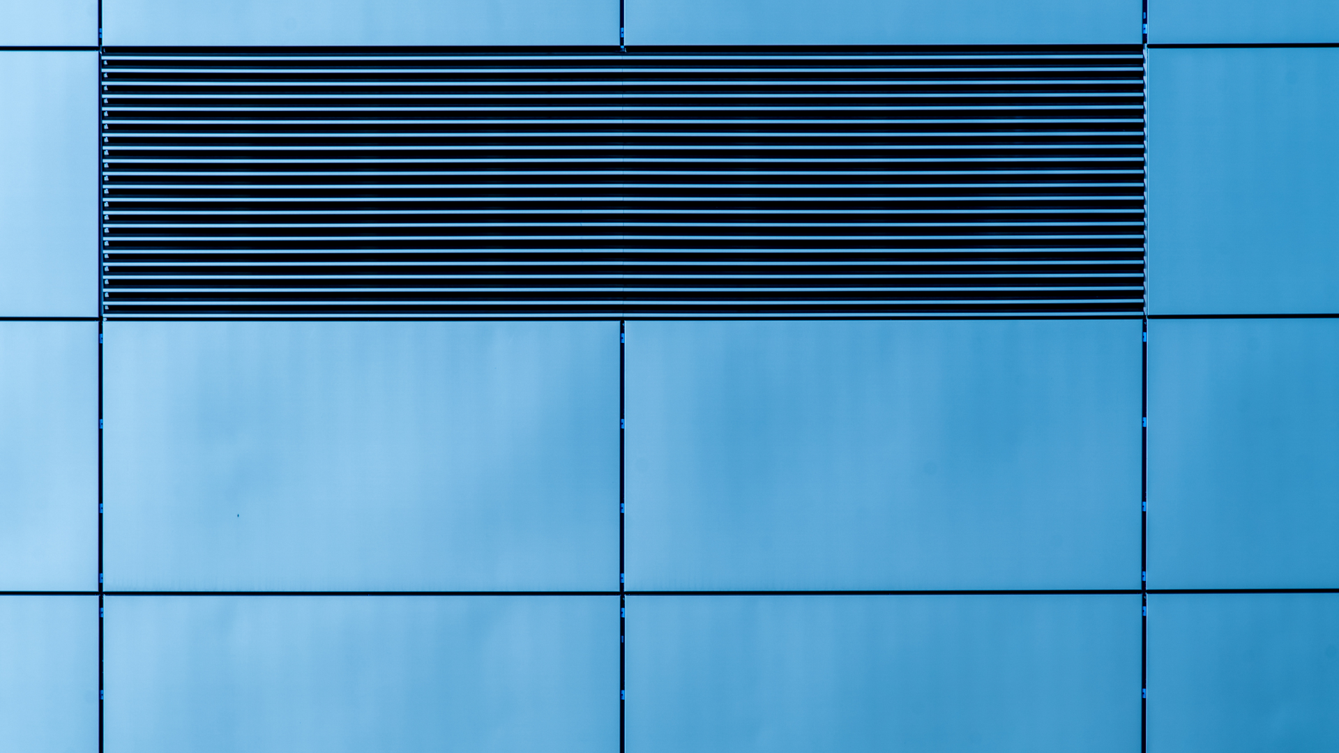 A close up of a blue building with a black grille on the side.