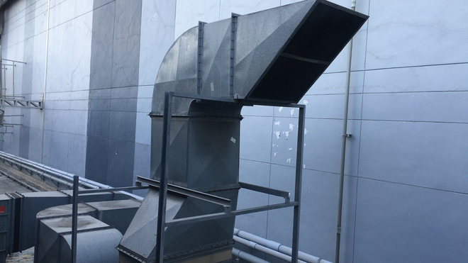 A large metal pipe is attached to the side of a building.