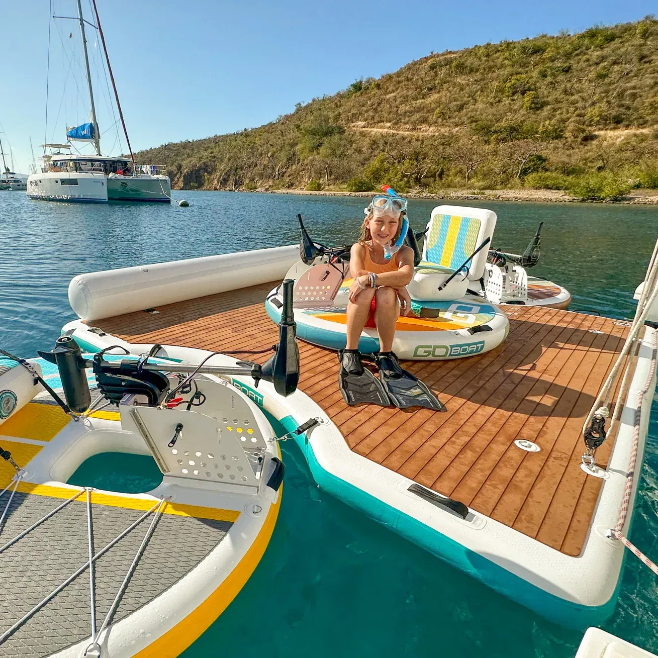 A woman is sitting on the deck of a boat in the water.