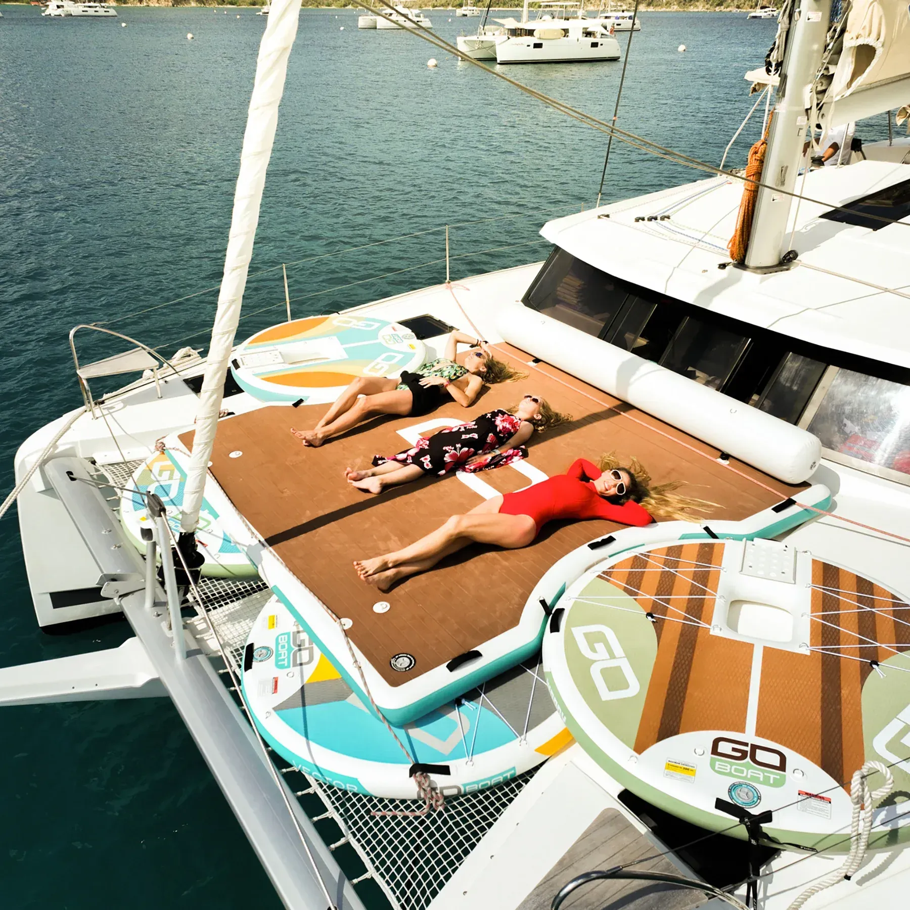 Three women are laying on the deck of a sailboat in the water.
